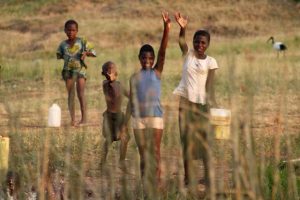 Kinderen zwaaien langs de oever van Queen Elizabeth National Park in Uganda